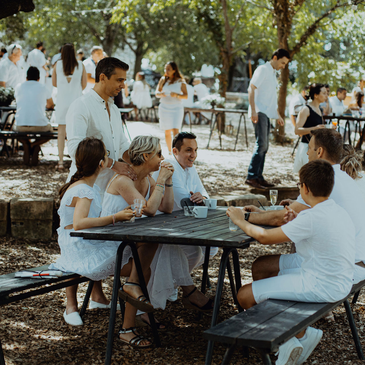 tables dans le jardin avec personnes participant à évènement privé en blanc